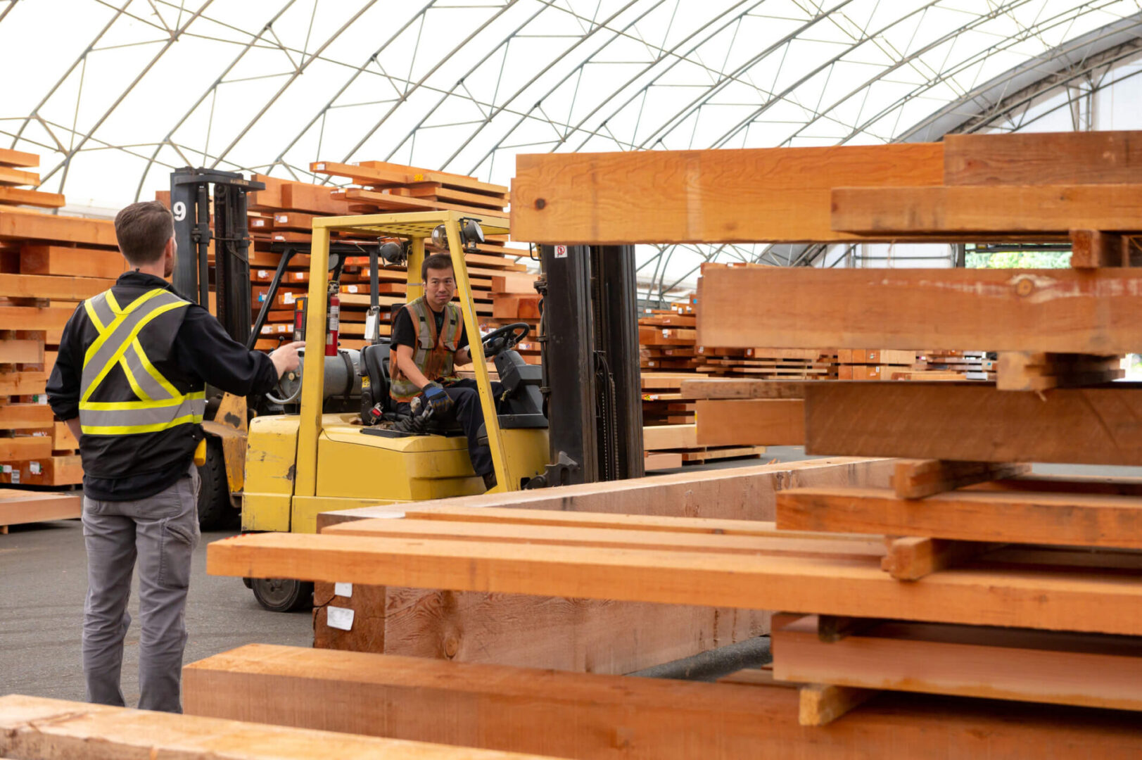 Workers moving lumber with a forklift