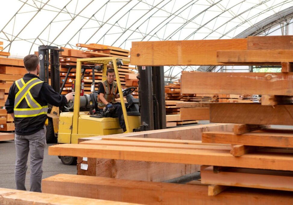Workers moving lumber with a forklift